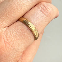 Gold ring on a person's finger against a neutral background