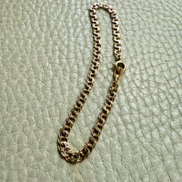 Gold chain bracelet on a light green textured surface