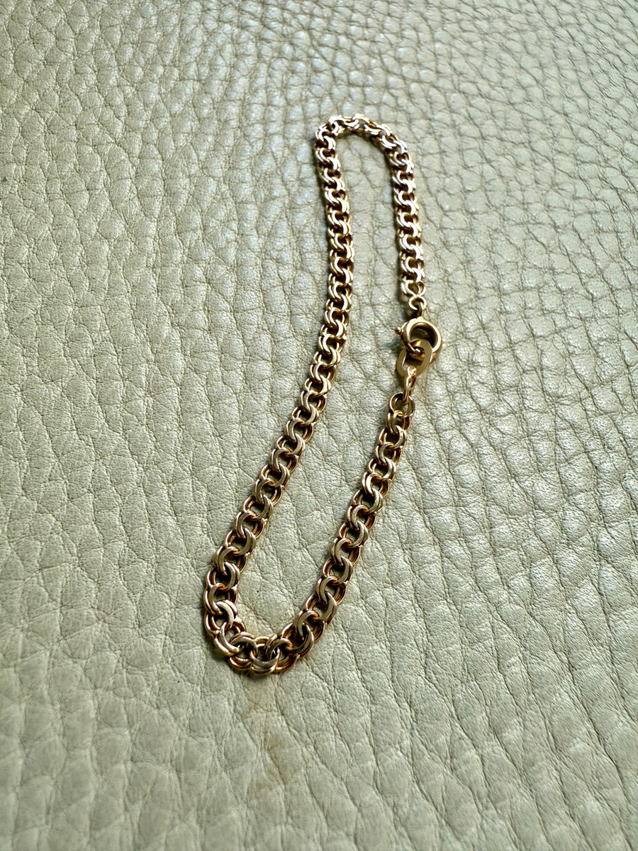 Gold chain bracelet on a light green textured surface