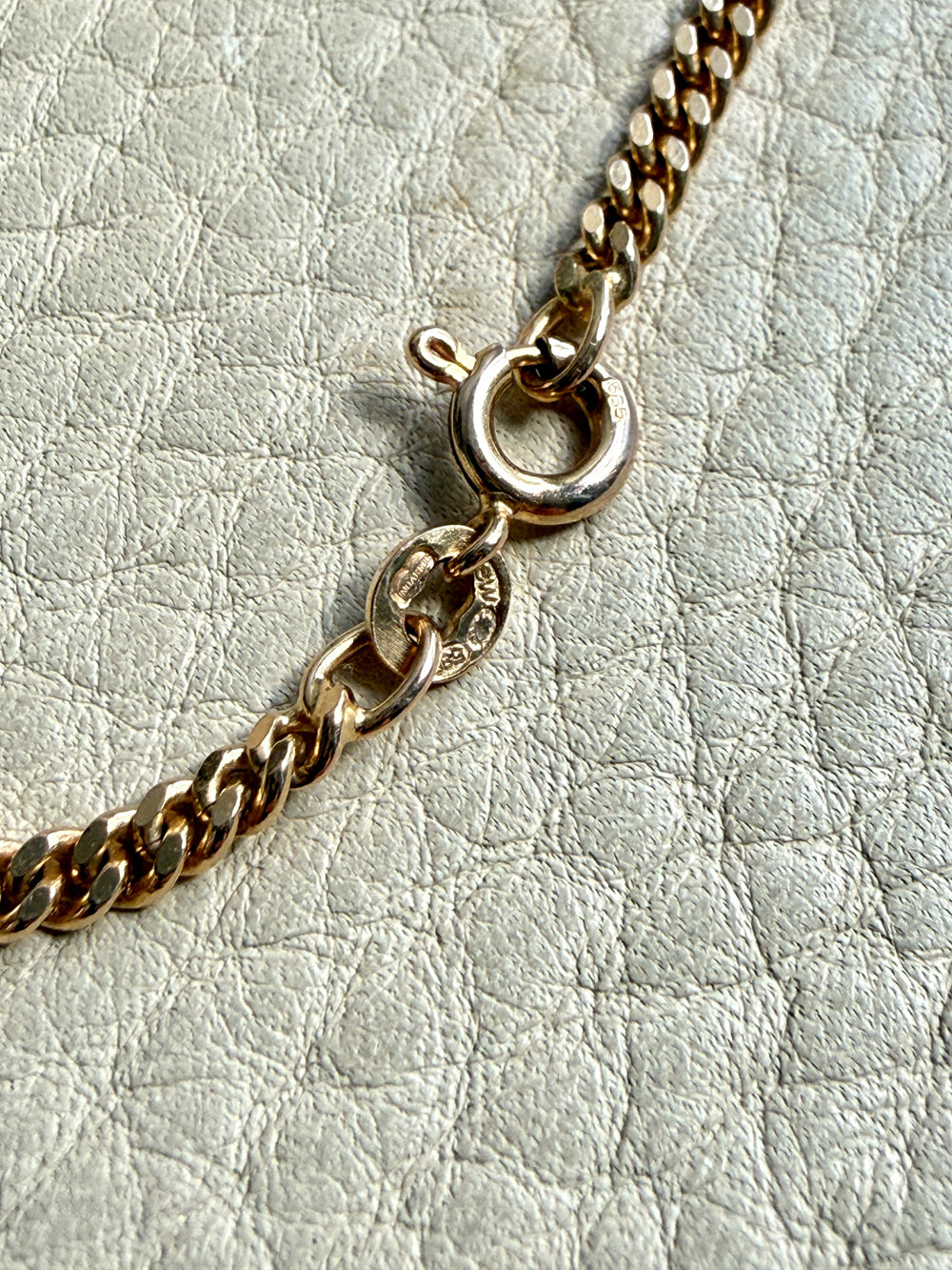 Gold chain bracelet on a light gray textured background