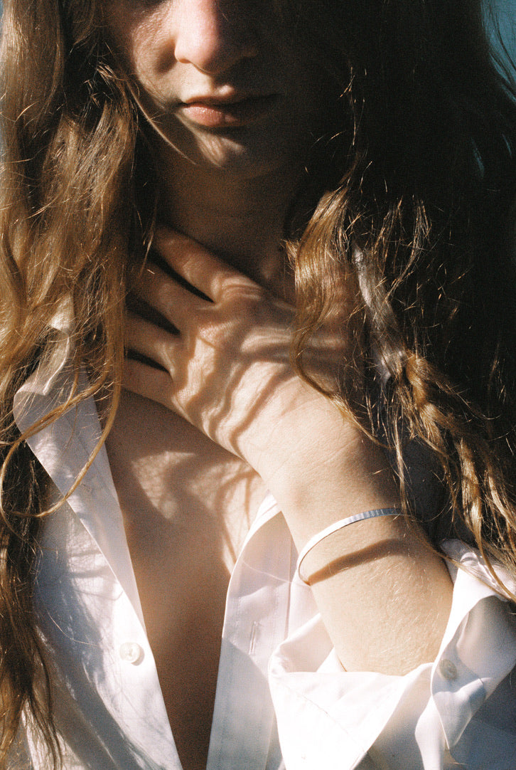 Close-up of a person wearing a white shirt with a white gold bangle