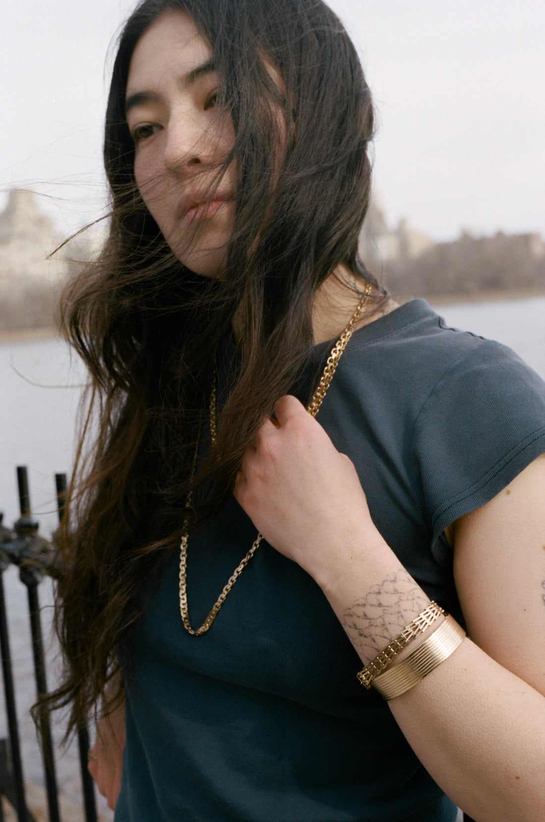 Woman wearing a gold necklace and bracelets with a blurred background