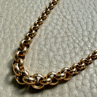 Gold chain necklace on a textured gray surface