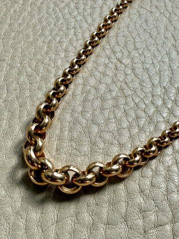 Gold chain necklace on a textured gray surface