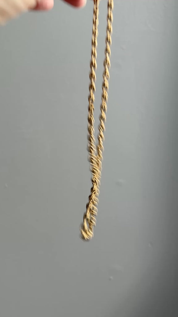 Gold chain necklace on a textured light gray background