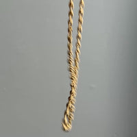 Gold chain necklace on a textured light gray background